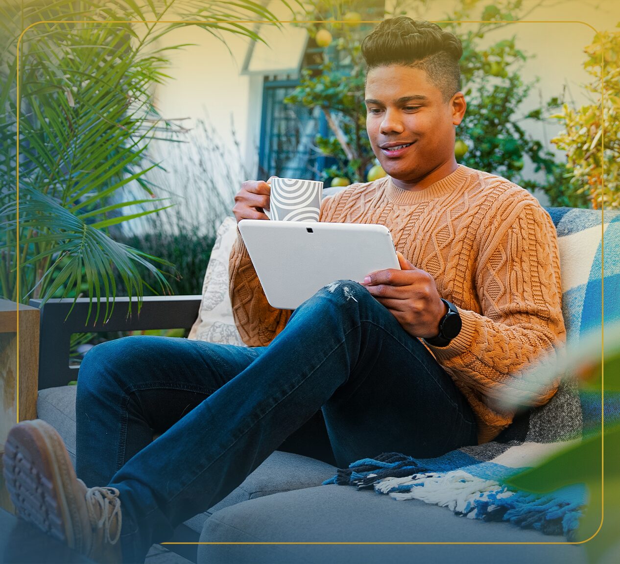 Black man with glasses smiles while reaching up to tend a tall garden plant