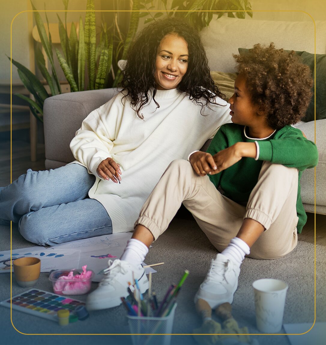 Child laughing while riding his toy car in the kitchen while his parents walk into the room.